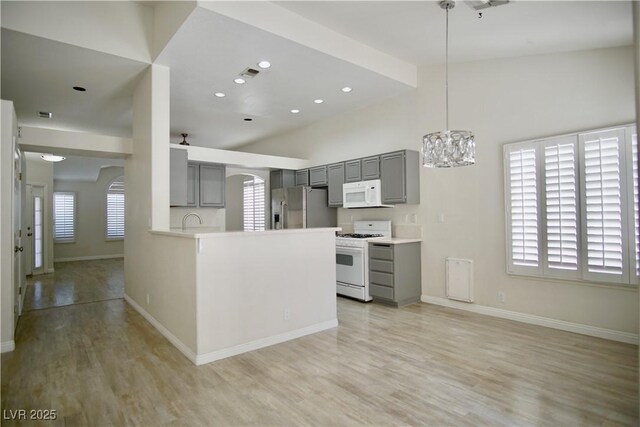 kitchen with white appliances, arched walkways, gray cabinets, light wood-type flooring, and a chandelier