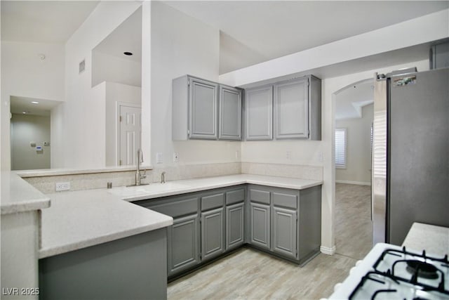 kitchen with a sink, light countertops, gray cabinets, and freestanding refrigerator