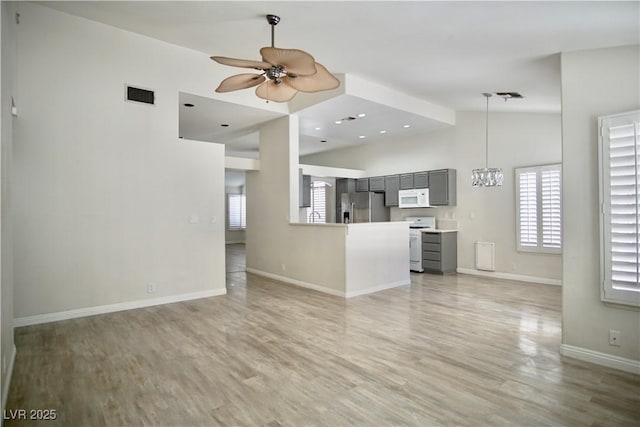 unfurnished living room with light wood-style floors, ceiling fan with notable chandelier, visible vents, and baseboards