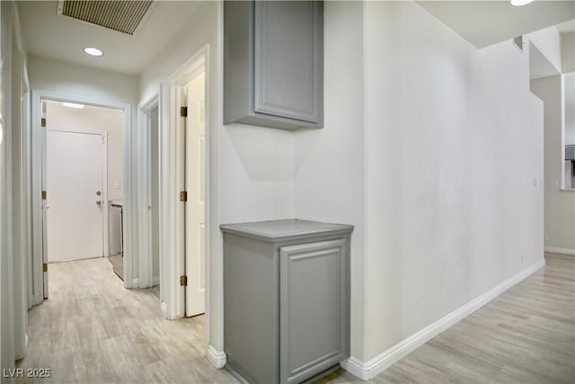 hallway with light wood-type flooring, visible vents, and baseboards