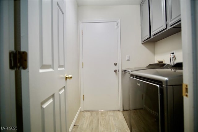 washroom featuring light wood-style flooring, cabinet space, independent washer and dryer, and baseboards