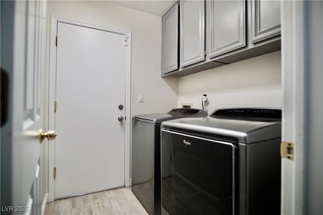 laundry room with cabinet space, independent washer and dryer, and light wood finished floors