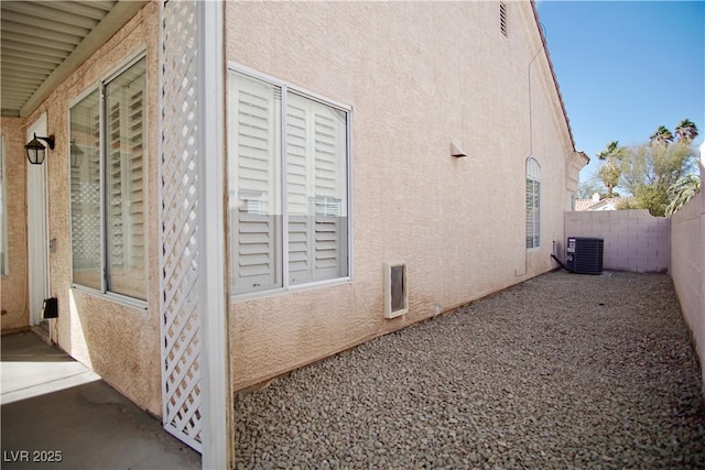 view of property exterior featuring fence private yard, central AC, and stucco siding