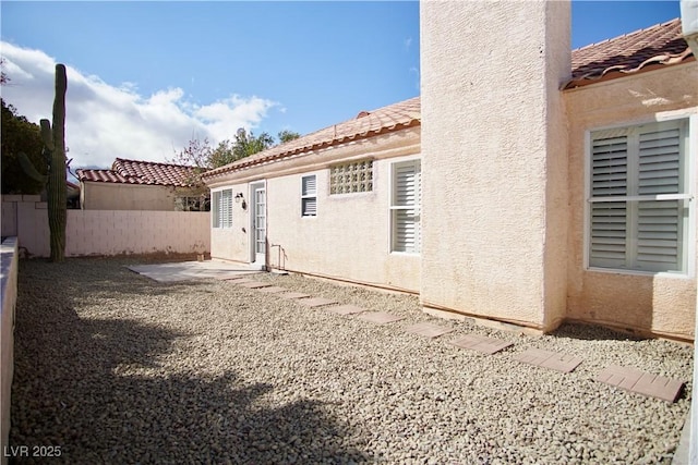 back of property featuring stucco siding, fence, and a tile roof