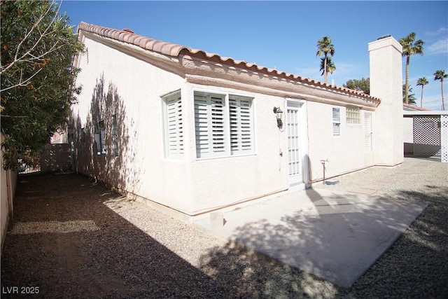 view of home's exterior with a chimney, a patio area, fence, and stucco siding