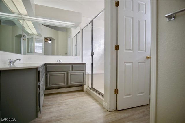 full bath featuring double vanity, wood finished floors, a stall shower, and a sink