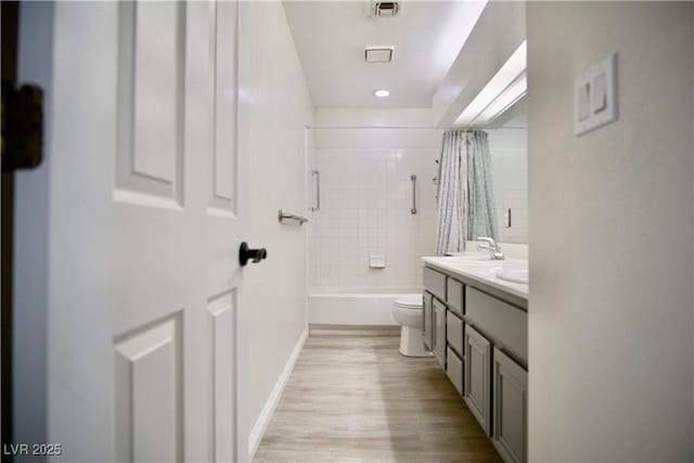 full bath with visible vents, toilet, shower / bath combo, wood finished floors, and vanity