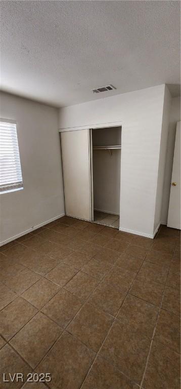 510 Holick Ave, Henderson, NV 89011 - unfurnished bedroom featuring a textured ceiling, a closet, and dark tile patterned floors