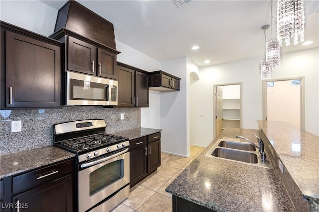 kitchen featuring light tile patterned flooring, a sink, dark brown cabinets, appliances with stainless steel finishes, and tasteful backsplash