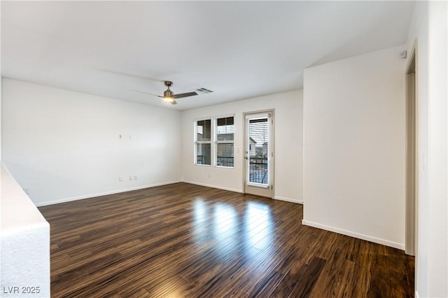 unfurnished room with dark wood finished floors, visible vents, baseboards, and a ceiling fan