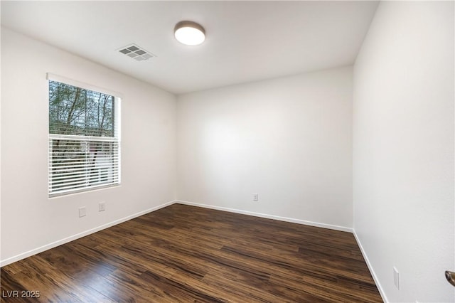 spare room featuring dark wood-style floors, visible vents, and baseboards