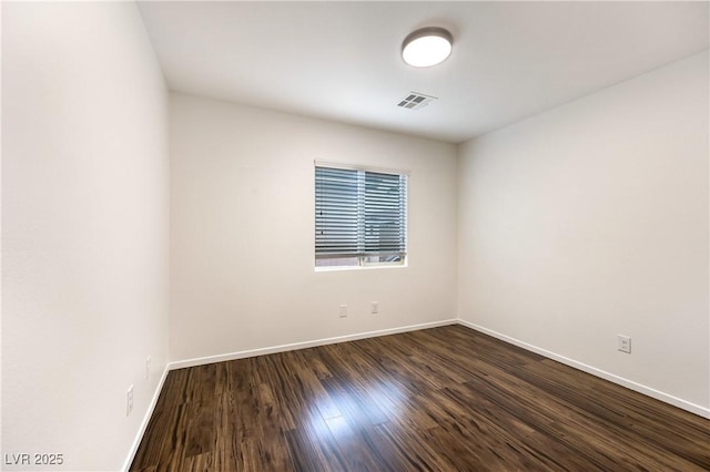 unfurnished room with dark wood finished floors, visible vents, and baseboards