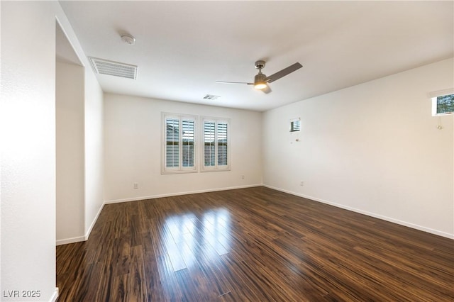 empty room with dark wood-style floors, visible vents, baseboards, and ceiling fan