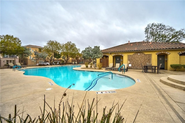 community pool with a patio area and fence