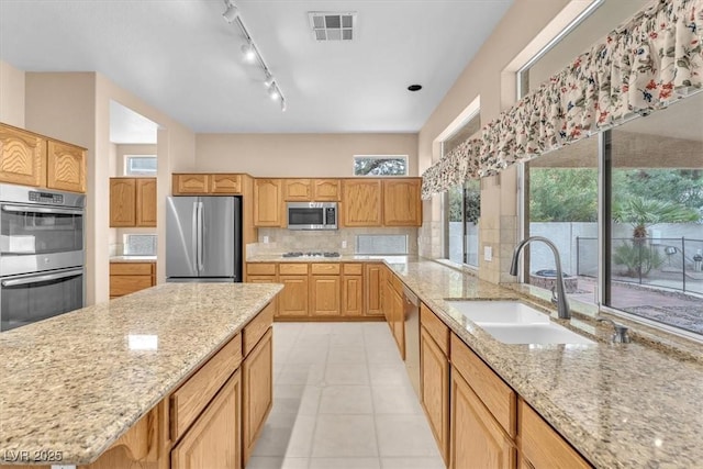 kitchen featuring visible vents, backsplash, light stone counters, appliances with stainless steel finishes, and a sink