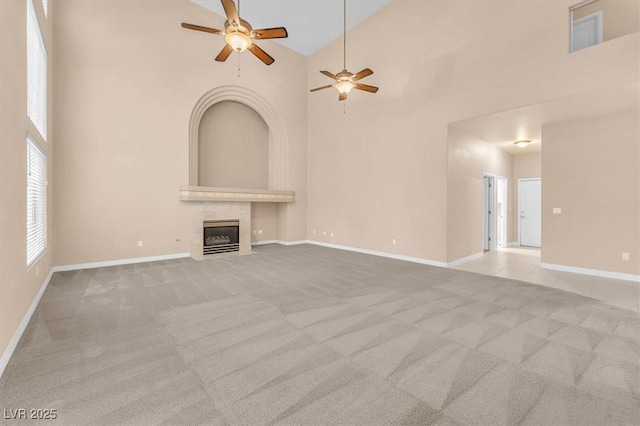 unfurnished living room with a ceiling fan, carpet, and a towering ceiling