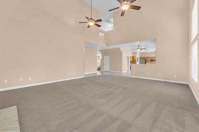 unfurnished living room with carpet, a ceiling fan, visible vents, and baseboards