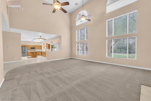 unfurnished living room featuring visible vents, a ceiling fan, baseboards, and light carpet