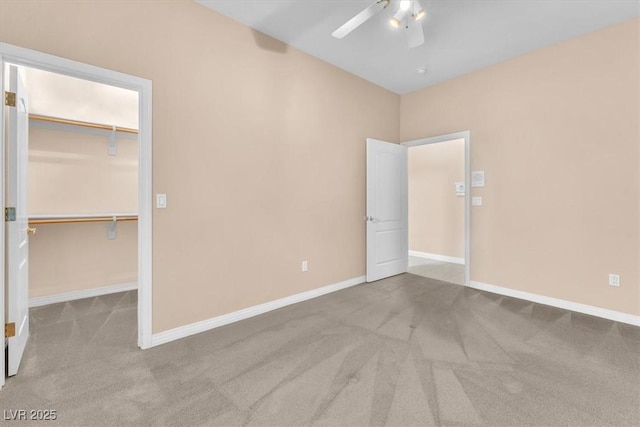 unfurnished bedroom with a walk in closet, ceiling fan, baseboards, carpet floors, and a closet