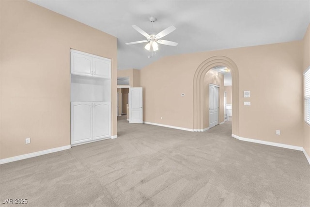 interior space featuring baseboards, arched walkways, carpet flooring, and vaulted ceiling