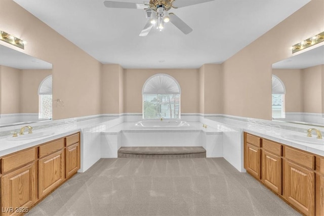 full bath featuring a ceiling fan, two vanities, a bath, and a sink