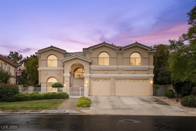 mediterranean / spanish-style house with stucco siding, concrete driveway, a garage, and fence