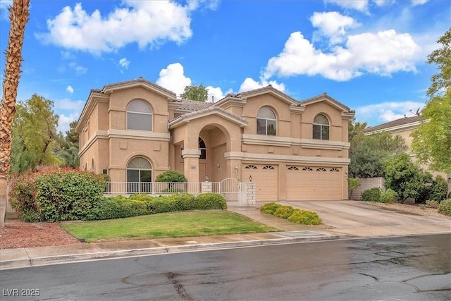 mediterranean / spanish-style home with stucco siding, driveway, a tile roof, fence, and an attached garage