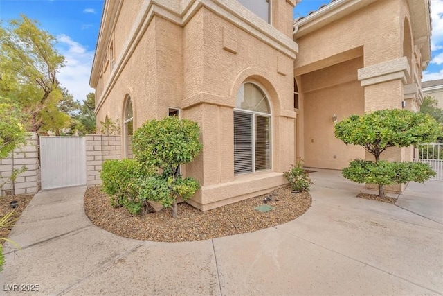 doorway to property with a patio area, a gate, fence, and stucco siding