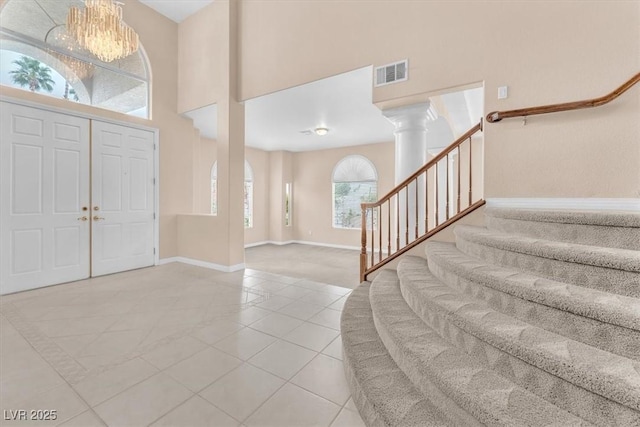 foyer entrance with visible vents, baseboards, stairway, an inviting chandelier, and a towering ceiling