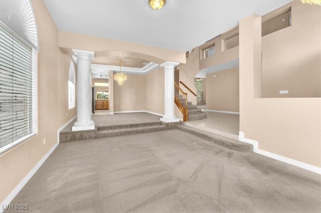 foyer entrance featuring baseboards, carpet flooring, and ornate columns