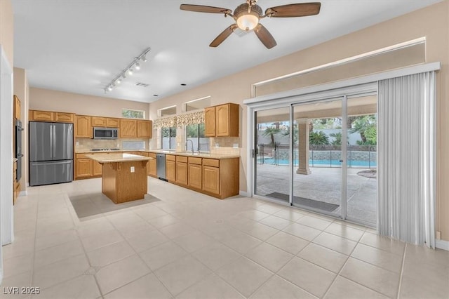 kitchen with stainless steel appliances, tasteful backsplash, a center island, and light countertops