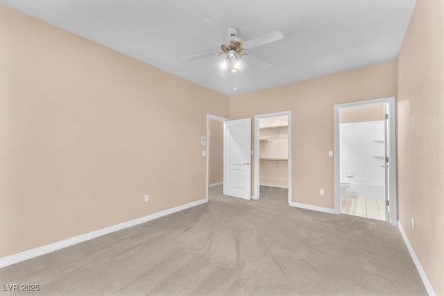 unfurnished bedroom featuring a spacious closet, a closet, baseboards, and carpet