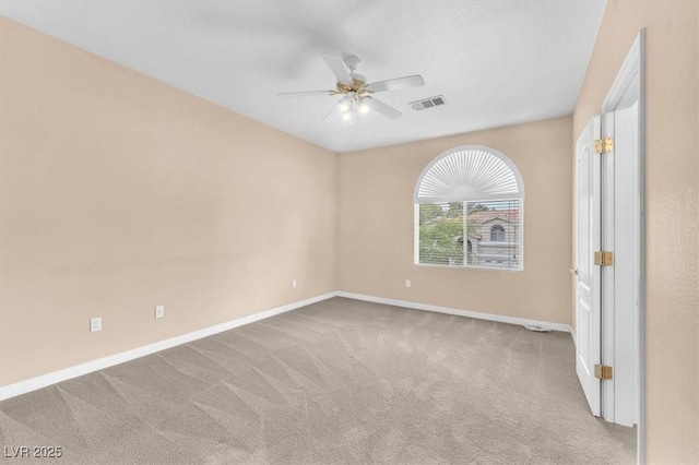 carpeted spare room featuring visible vents, baseboards, and a ceiling fan