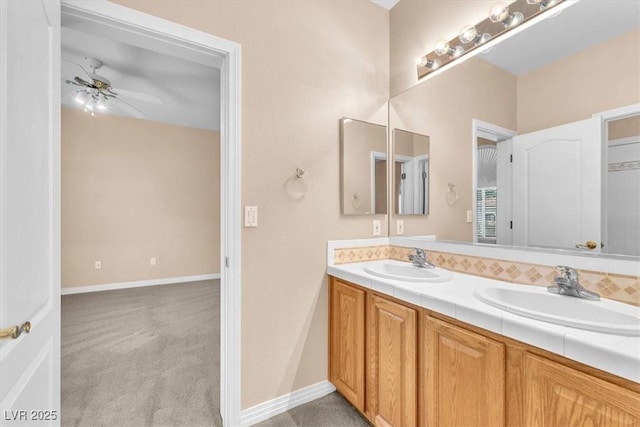 bathroom featuring double vanity, baseboards, ceiling fan, and a sink