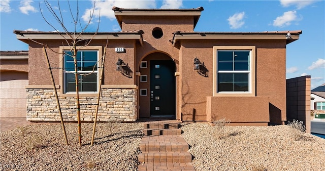 view of front facade featuring stone siding and stucco siding