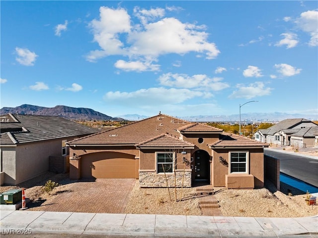 view of front of home featuring an attached garage, stucco siding, stone siding, a tile roof, and decorative driveway