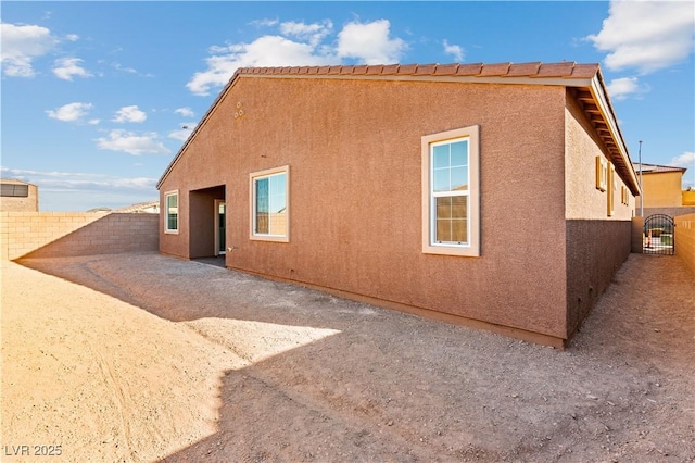 rear view of property with a gate, stucco siding, and fence