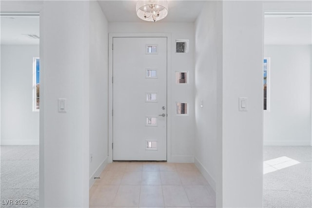 interior space featuring light tile patterned floors, visible vents, baseboards, and a notable chandelier