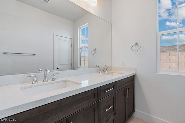 full bath with double vanity, baseboards, and a sink