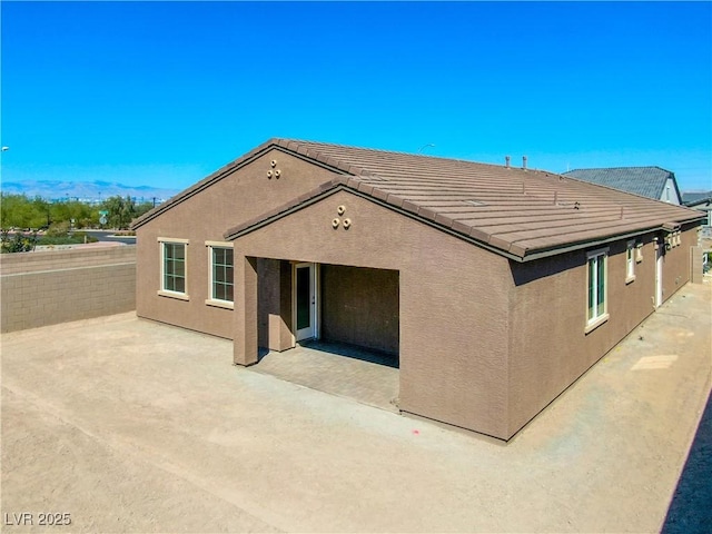 back of property featuring stucco siding, a tile roof, and a patio