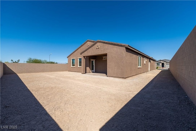 rear view of house with a fenced backyard and stucco siding