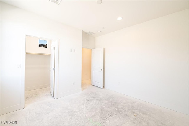 unfurnished bedroom with recessed lighting, a walk in closet, and baseboards