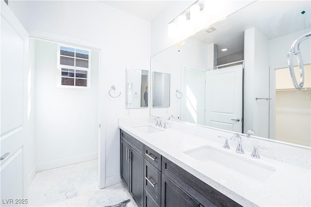 bathroom with double vanity, visible vents, baseboards, and a sink