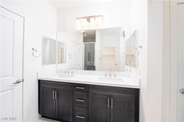 full bathroom featuring double vanity, a spacious closet, a stall shower, and a sink