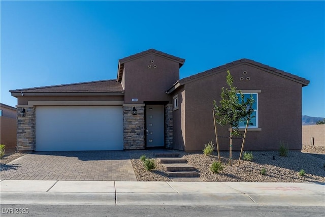 view of front of house with a tile roof, decorative driveway, a garage, and stucco siding