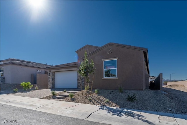 view of front of house featuring stucco siding, stone siding, an attached garage, and driveway