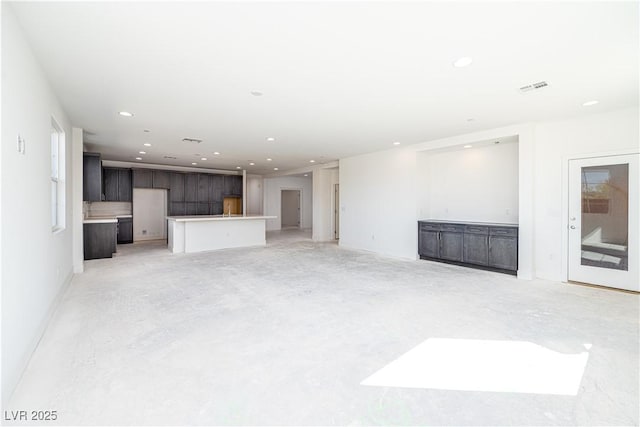 unfurnished living room featuring recessed lighting, visible vents, and concrete flooring