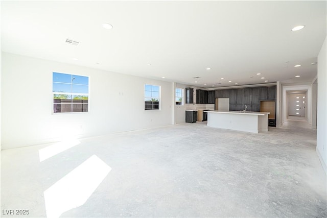 unfurnished living room with recessed lighting, visible vents, concrete floors, and a healthy amount of sunlight