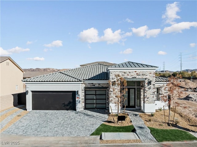 view of front of house featuring stucco siding, a garage, stone siding, a tile roof, and decorative driveway