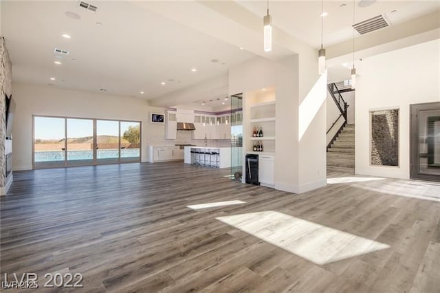 unfurnished living room with visible vents, wine cooler, and wood finished floors